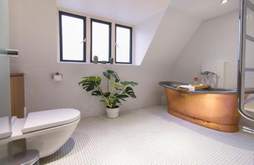 a bathroom with a tub and a plant in it at Casa lujosa de 4 habitaciones cerca un minuto de la estación in London