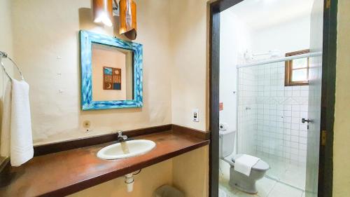 a bathroom with a sink and a toilet and a mirror at Hotel e Pousada Canto Mágico in Maresias