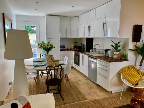 una cucina con mobili bianchi, un tavolo e una sala da pranzo di CHALET BTZ a Biarritz