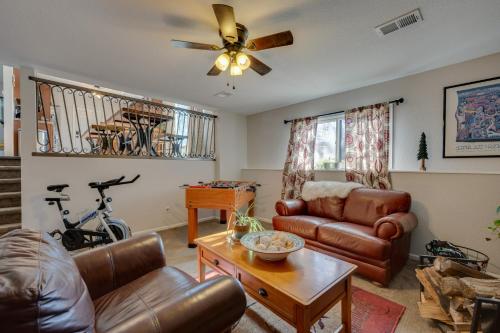 a living room with leather furniture and a ceiling fan at Loveland Home with Private Hot Tub and Wood Fireplace! in Loveland