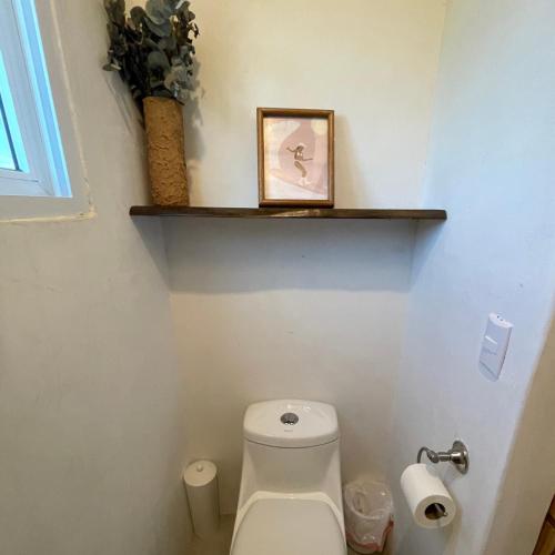 a bathroom with a toilet with a shelf on the wall at Wander Boutique Hotel in El Paredón Buena Vista