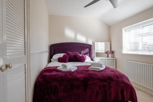 a bedroom with a purple bed with towels on it at Ashbourne House - Close to Central Woking in Woking