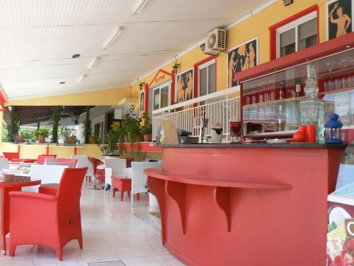 a restaurant with a red counter and tables and chairs at Hotel Dias Apartment in Makrýgialos