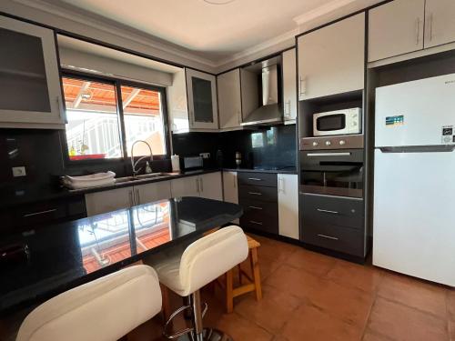 a kitchen with black and white cabinets and white appliances at Pink House in Ponta do Sol