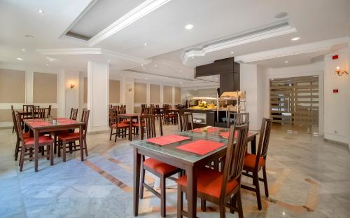 a dining room with tables and chairs and a kitchen at El Oumara Hotel in Tunis