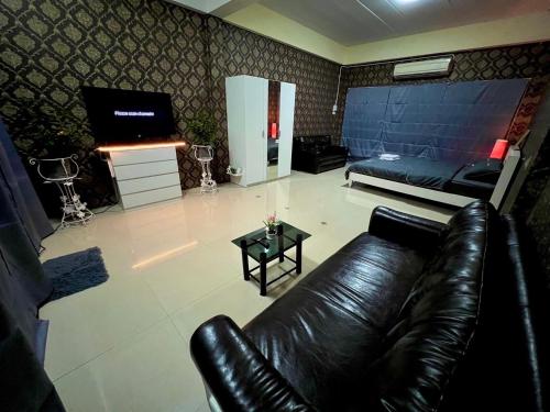 a living room with a leather couch and a television at Future Hostel Pattaya in Nong Prue