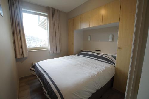 1 dormitorio con 1 cama grande y ventana en Delphine, en Koksijde