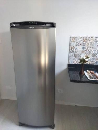 einem Kühlschrank aus Edelstahl neben einer Wand in der Unterkunft Kitnet 1 - próximo ao centro de Jacareí in Jacareí