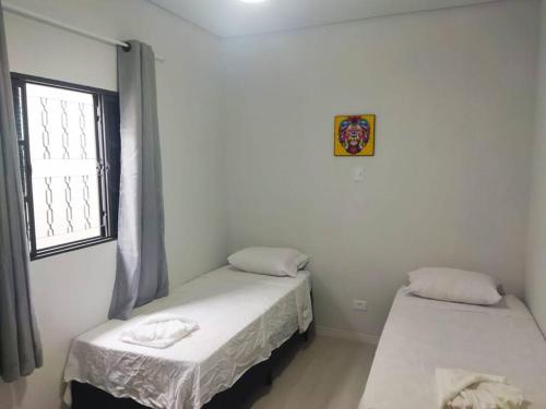2 camas individuais num quarto com uma janela em Kitnet 1 - próximo ao centro de Jacareí em Jacareí
