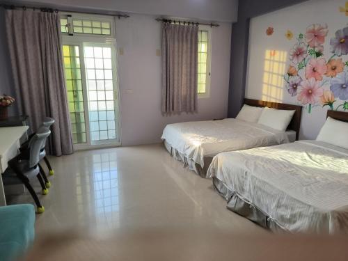 a bedroom with two beds and a desk and windows at Vineyard Guest House in Taitung City