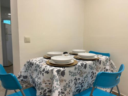 une table avec des assiettes et des chaises bleues dans l'établissement Apartamento Alcalá, à Madrid