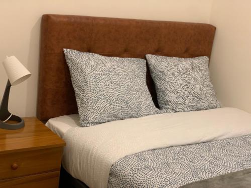 ein Bett mit zwei Kissen und einer Lampe auf einem Tisch in der Unterkunft Apartamento Alcalá in Madrid