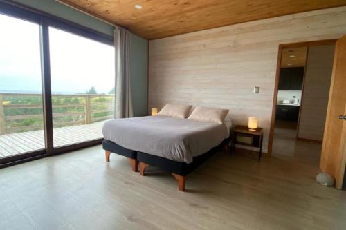 1 dormitorio con cama y ventana grande en Casa La Laguna - Pichilemu, en Pichilemu