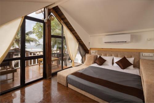 a bedroom with a large bed and a balcony at Forget Me Not Resort in Agonda