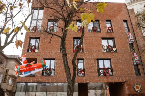 a building with a christmas elf balloon hanging from a tree at 26Bricks Luxury Suites in Oradea