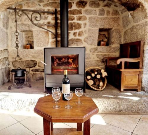 a table with two wine glasses and a fireplace at Maison paysanne, proche Aubrac in Huparlac