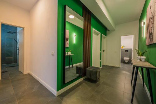a hallway with green walls and a mirror at TheMuseApartament in Alba Iulia