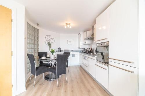 een keuken met witte kasten en een tafel en stoelen bij Luxury Riverview City Centre Apartment 2 in Glasgow