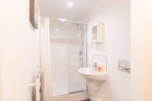 een witte badkamer met een douche en een wastafel bij Luxury Riverview City Centre Apartment 2 in Glasgow