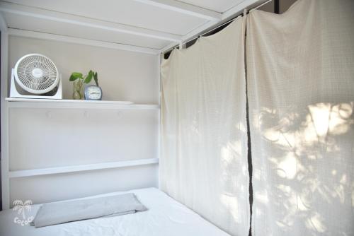 a bedroom with a white curtain and a fan at CoCoCo in Ko Phayam