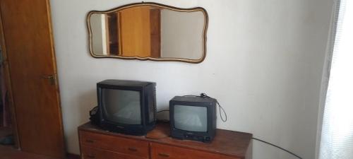 dos televisores sentados en un tocador bajo un espejo en SantaTeresita en Santa Teresita