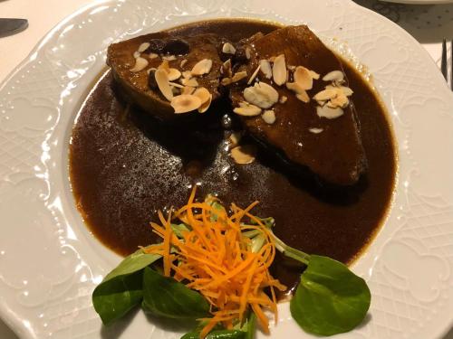 a white plate with a dessert with brown sauce and nuts at Hotel-Restaurant Denklinger-Hof in Reichshof 