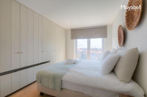 a bedroom with a white bed with a window at Appartement op de zeedijk in Knokke voor 7 personen in Knokke-Heist