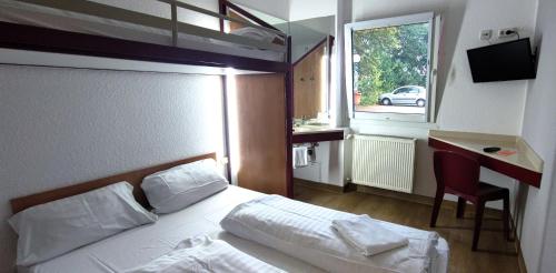 a bedroom with a bed and a desk and a window at Motel 24h Hannover in Hannover