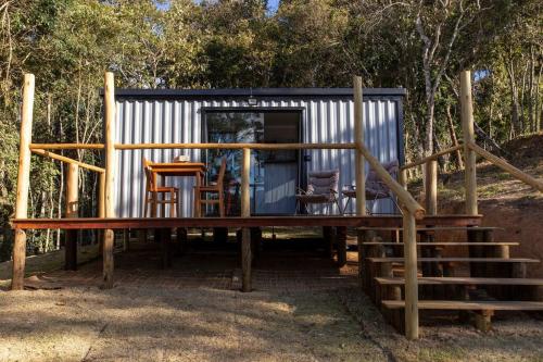 a tiny house with a porch and some chairs at Chalé Container do Beijo in Campos do Jordão