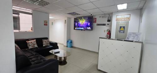 una sala de espera con sofá y TV en la pared en HOTEL TICLIO, en Cajamarca