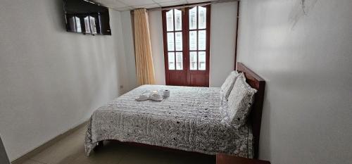 Un dormitorio con una cama con dos zapatos. en HOTEL TICLIO, en Cajamarca