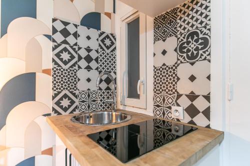 La salle de bains est pourvue d'un lavabo et de carrelage noir et blanc. dans l'établissement MBA Splendide Appart Saint-Michel Paris Centre, à Paris