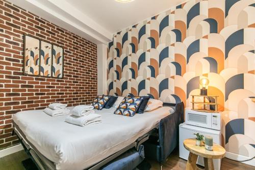 un lit dans une chambre avec un mur de briques dans l'établissement MBA Splendide Appart Saint-Michel Paris Centre, à Paris