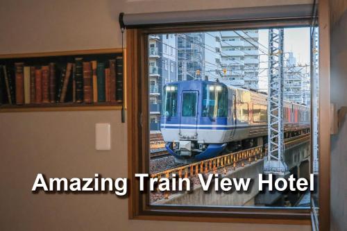 a train is on the tracks through a window at 2024年1月開業トレインビューホテル梅田 in Osaka
