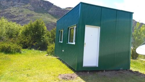 a green tiny house with a white door at Fitz Roy Hostería de Montaña - El Chaltén in El Chalten