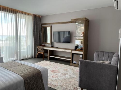 a hotel room with a bed and a desk with a television at Tabebuya Resto & Resort in Kesembu