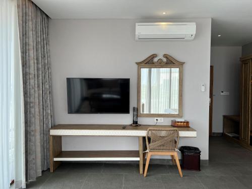 a room with a desk with a television and a chair at Tabebuya Resto & Resort in Kesembu