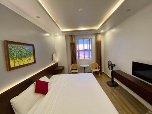 een slaapkamer met een groot bed en een televisie bij Dolphin Hotel in Cat Ba