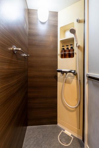 a bathroom with a shower and a wooden door at 2024年1月開業トレインビューホテル梅田 in Osaka