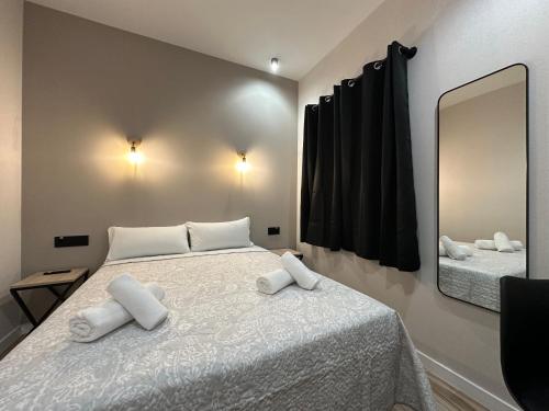 a bedroom with a bed with white pillows and a mirror at CC Opera Suites in Madrid