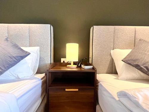 a nightstand between two beds with a lamp on it at HillMark Suites in Ayer Keroh