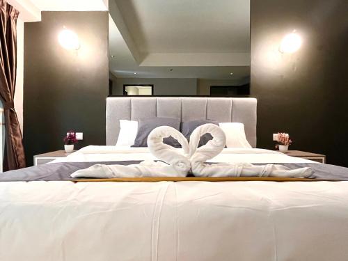 a bed with two white towels on top of it at HillMark Suites in Ayer Keroh