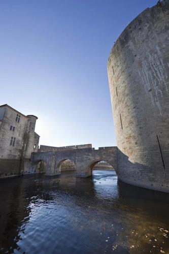 a stone bridge over a river next to a castle at La Villa Mazarin in Aigues-Mortes
