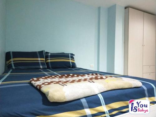 a bedroom with a bed with blue and yellow stripes at IsYou Sabye ห้องพักรายวัน รามคำแหง in Ban Zong Katiam