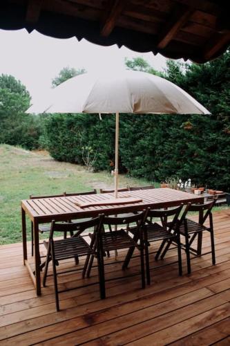 une table en bois avec un parasol sur une terrasse dans l'établissement Maison Typique Landaise, à Moliets-et-Maa
