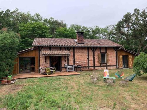 a house with a deck and chairs in the yard at Maison Typique Landaise in Moliets-et-Maa
