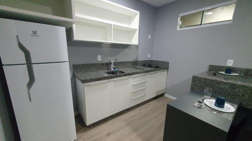 a kitchen with white cabinets and a white refrigerator at Yes Vancouver Flats in Corumbá