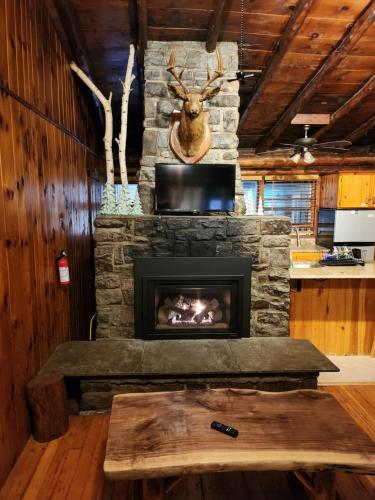 una chimenea de piedra en una sala de estar con mesa en Adirondack Diamond Point Lodge, en Lake George