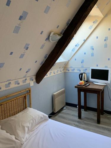 une chambre avec un lit et un bureau avec un ordinateur dans l'établissement Le Grillon, à Pontorson
