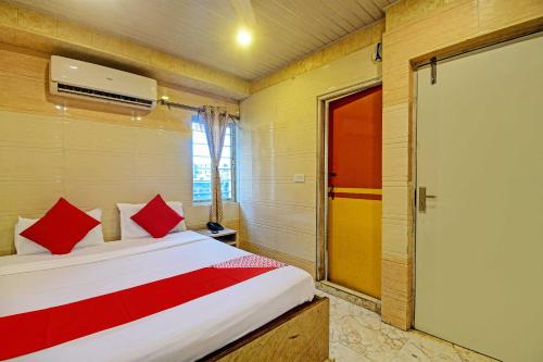 a bedroom with a bed with red pillows and a door at Hotel Royal Inn in Kolkata